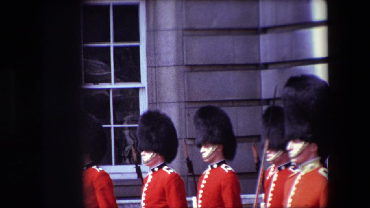 Red-uniformed guards in tall black hats march past a stone building exterior.