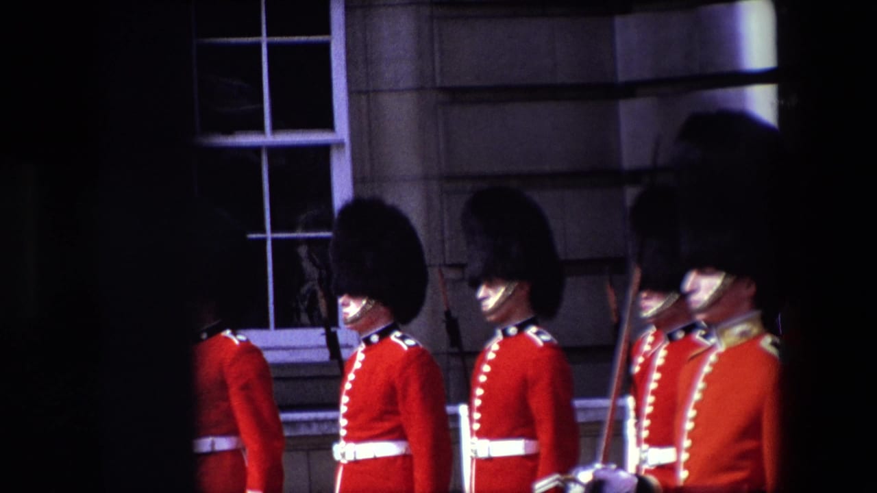 Line of red-uniformed guards standing or marching beside a stone building.