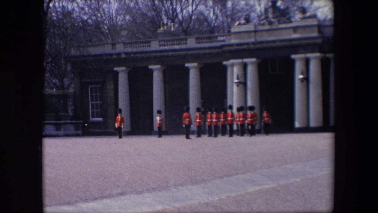 Uniformed guards stand and march near white columns on a paved forecourt.