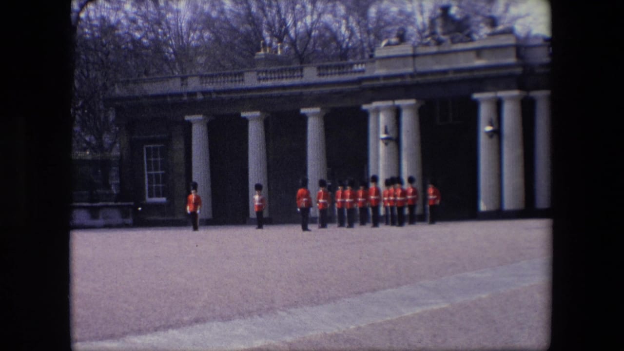 A line of guards stands in front of a columned building with bare trees behind it.