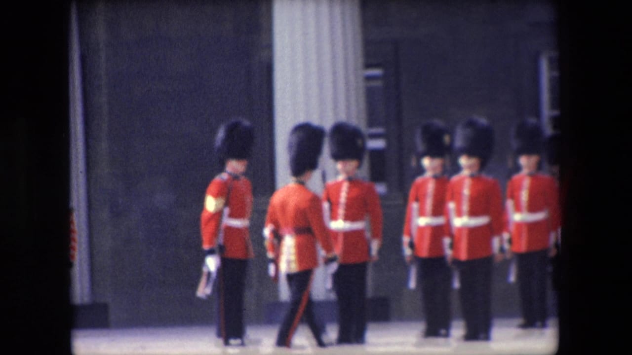 A guard marches in front of a line of soldiers in red ceremonial uniforms.