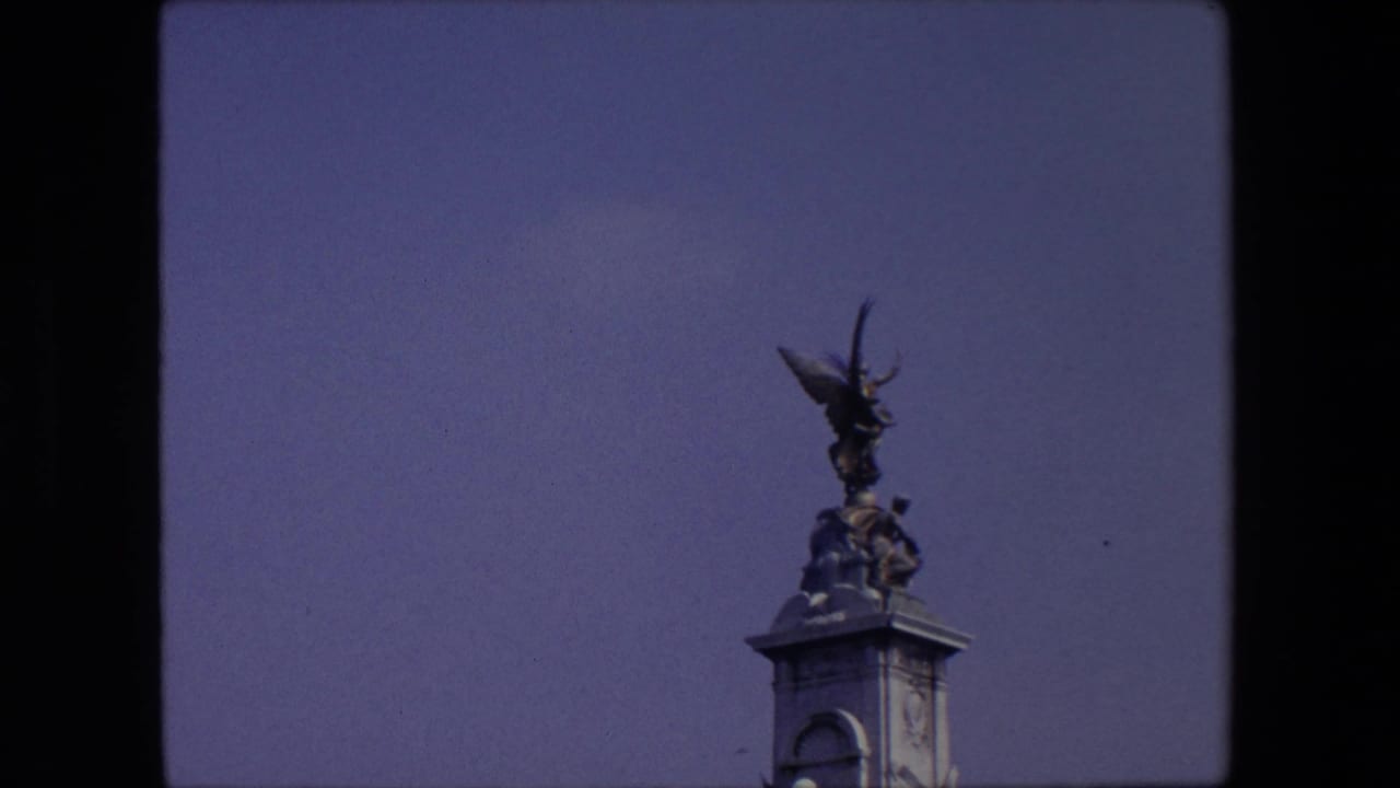 Winged statue and figures atop a stone pillar against blue sky.