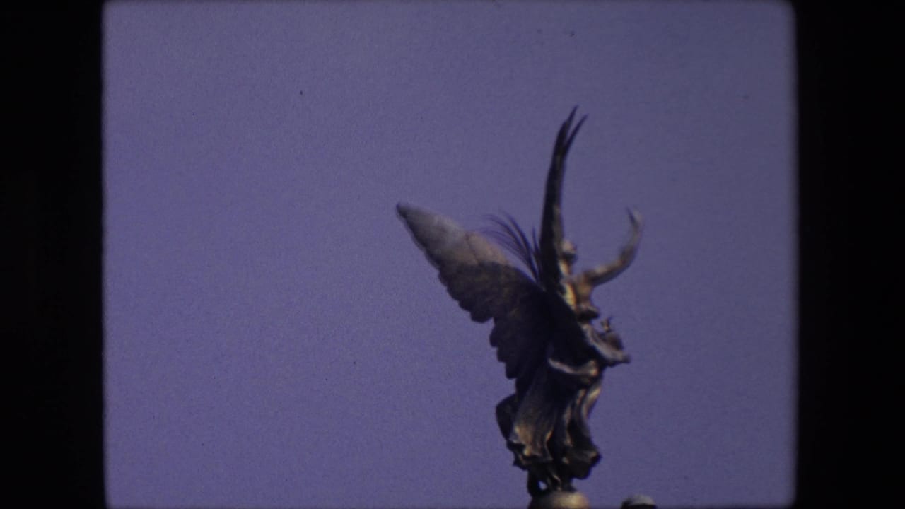 Winged statue seen against blue sky within a film contact-sheet frame.