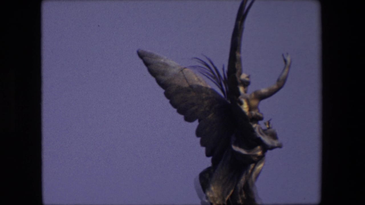 Closer view of a winged stone figure with raised arm and large feathered wing.