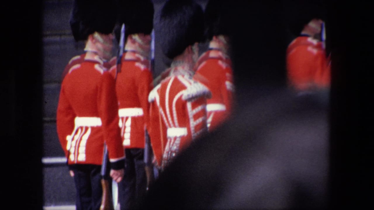 Red-uniformed guards seen from behind near dark gate bars.