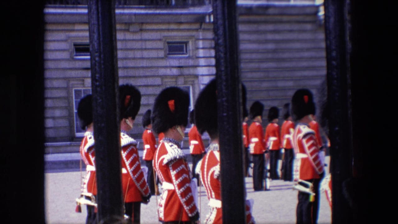 British Royal Guards in red uniforms stand at attention behind foreground railings.