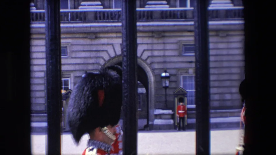 1967 London frame with a close foreground guard in red ceremonial dress and distant sentries outside the 10 Downing Street building.