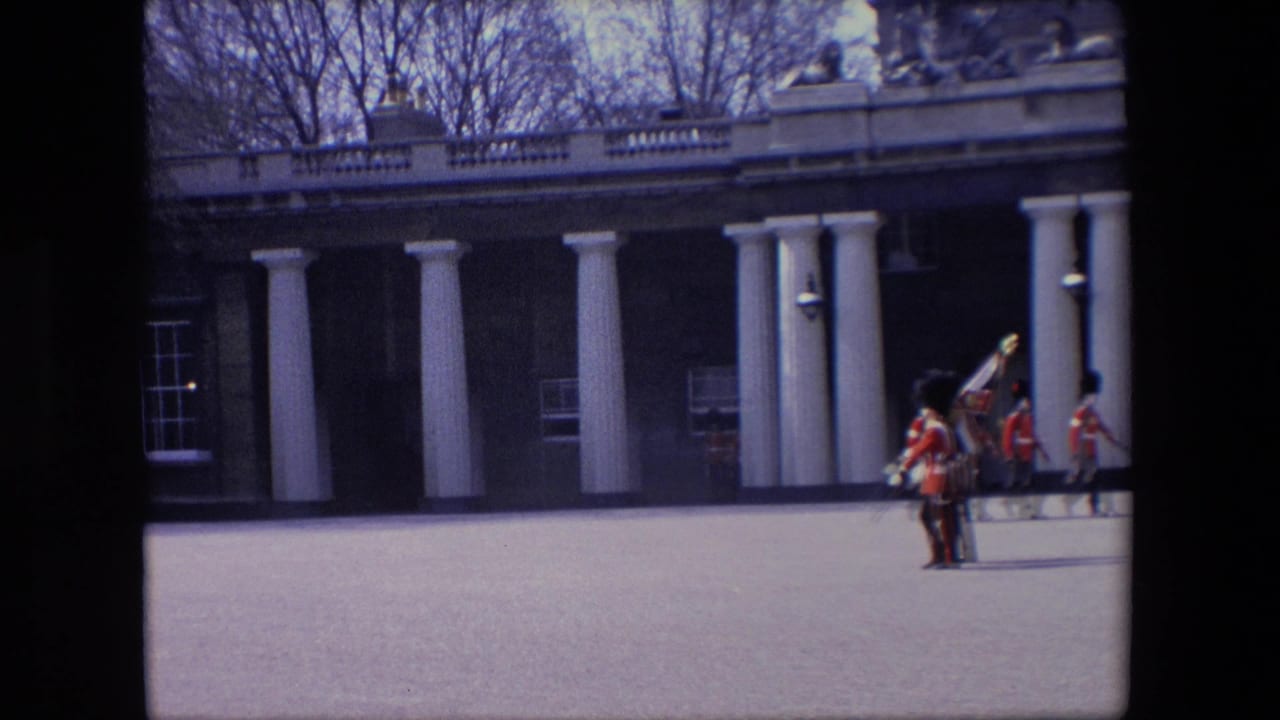 Two uniformed guards with flags continue marching across a parade ground.