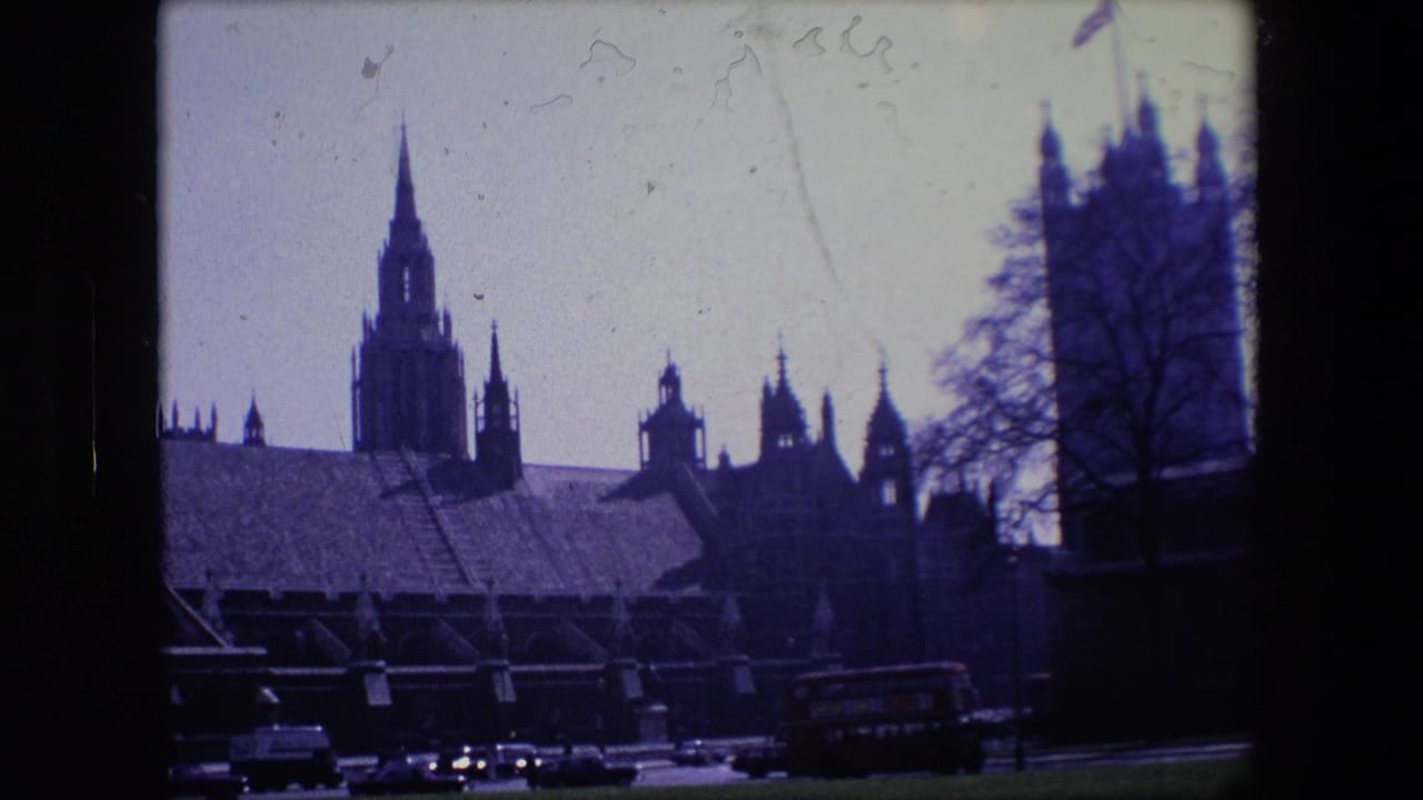 Silhouetted Gothic towers above a road with cars and a red double-decker bus.