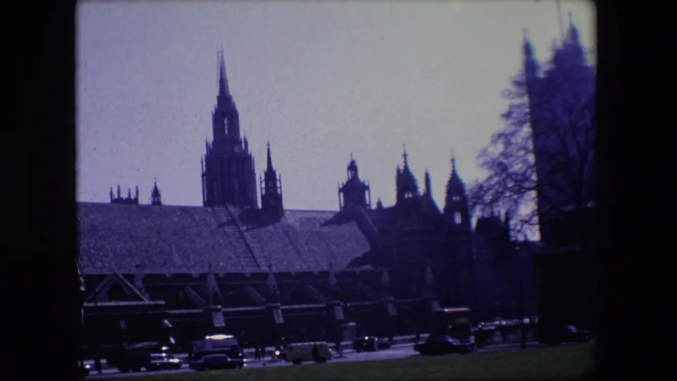 The final frame holds on London historic architecture in silhouette, with cars and a red double-decker bus moving along the road below.