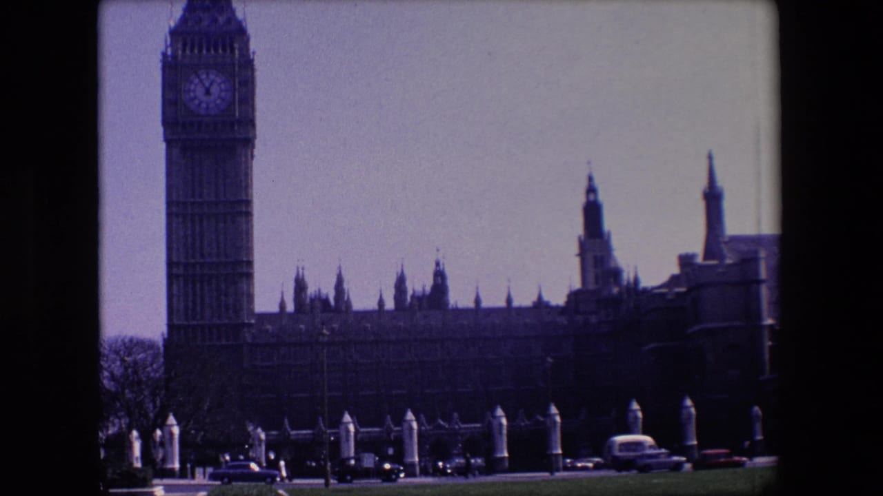 Big Ben at left with Westminster buildings and cars along the road.