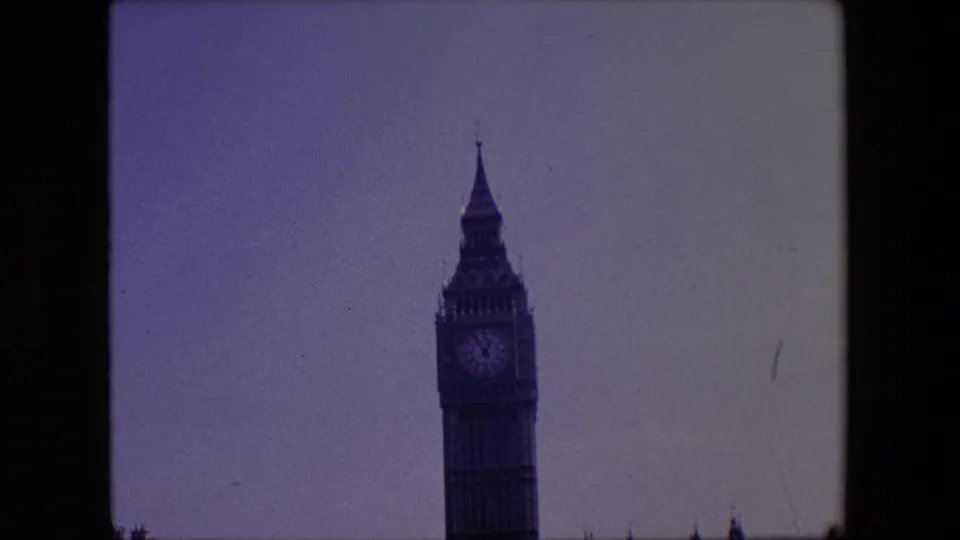 1967 London frame showing the upper clock tower of Big Ben above a low parliamentary roofline, with soft 8mm color and rounded frame edges.