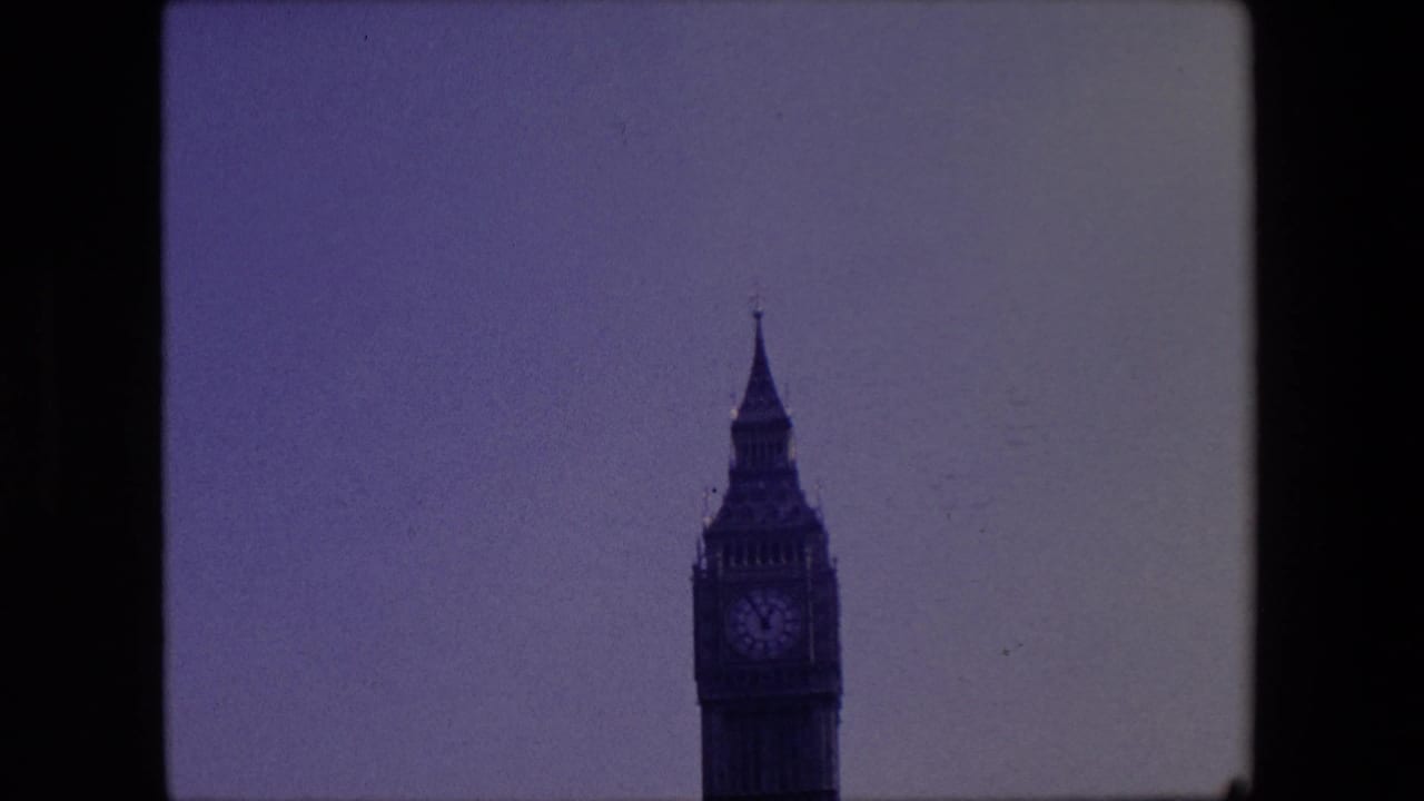 Telephoto 8mm view of the Elizabeth Tower upper section in London, centered against a pale sky with the clock face visible but soft.