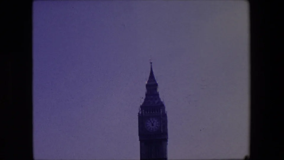 Telephoto 8mm view of the Elizabeth Tower upper section in London, centered against a pale sky with the clock face visible but soft.