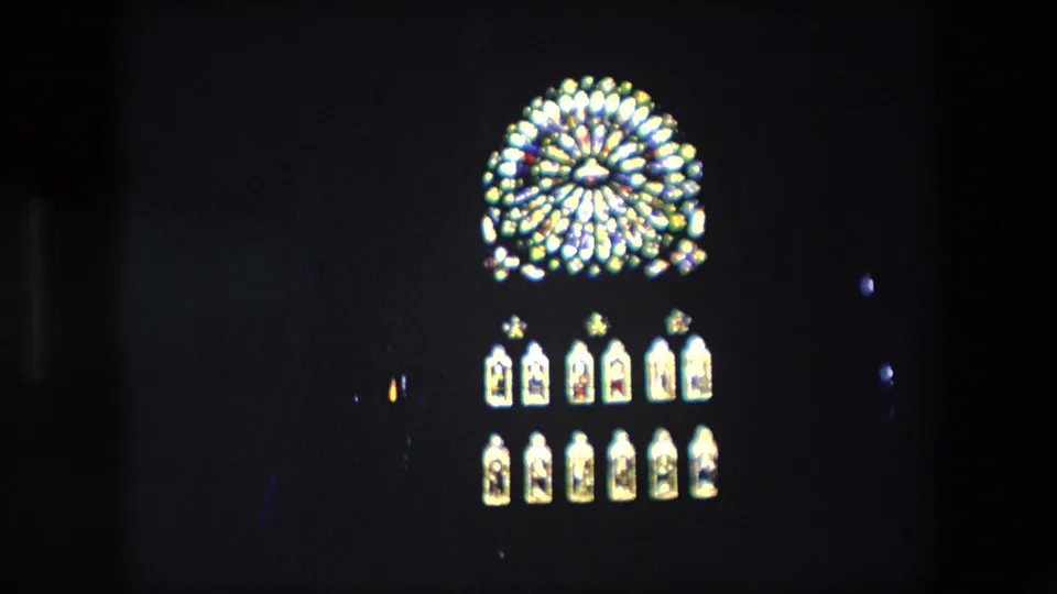 Dark 8mm frame from London in 1967 with a bright circular illuminated architectural or clock detail and two rows of smaller lit arches.