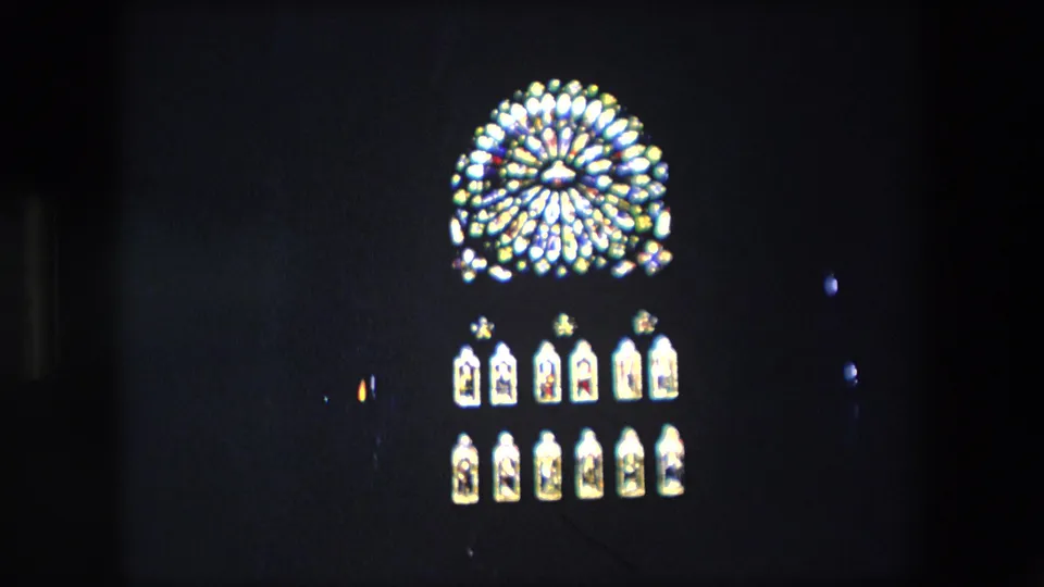 The camera sits slightly lower on the glowing circular feature and arched light panels, with low-light grain and dark surrounding architecture visible.