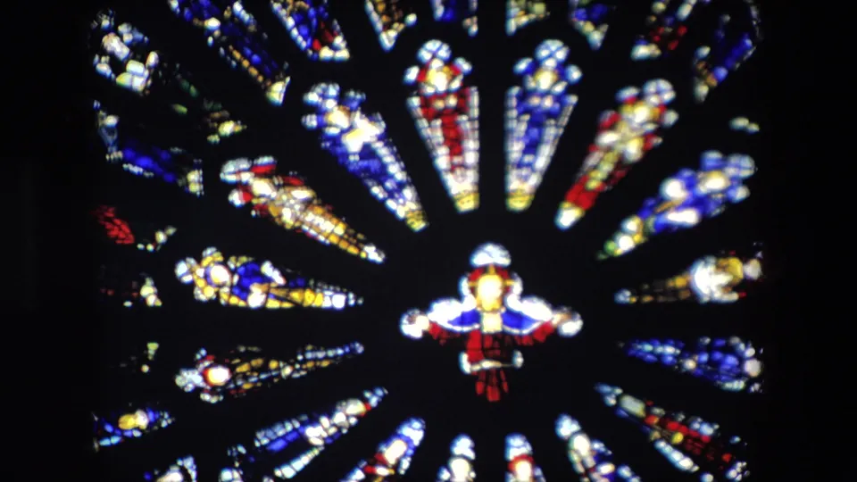 Final frame from the 1967 London church clip showing repeated stained glass segments around a small figure, with strong contrast between illuminated glass and the dark interior.