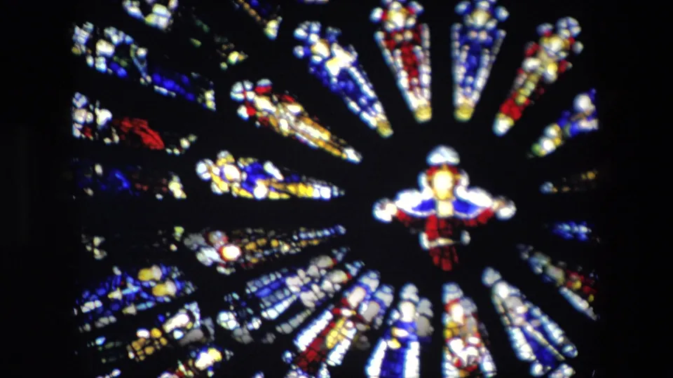 1967 London frame with the stained glass circle shifted in view, showing vivid red, blue, yellow, and white panels separated by dark lead lines.