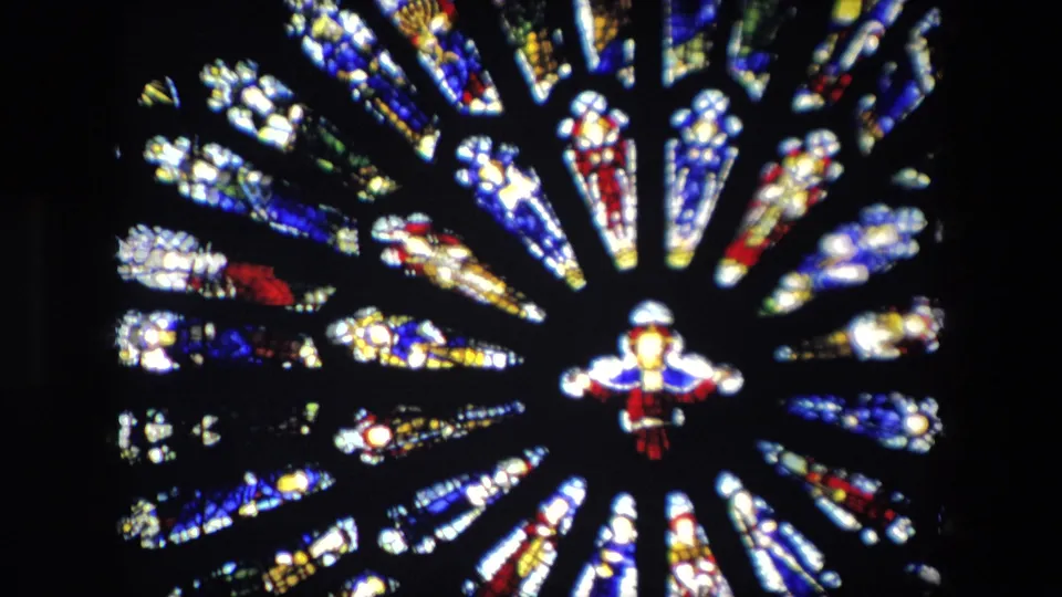 1967 London home-movie still showing a large circular stained glass design with radiating colored panels and a small central figure-like form.