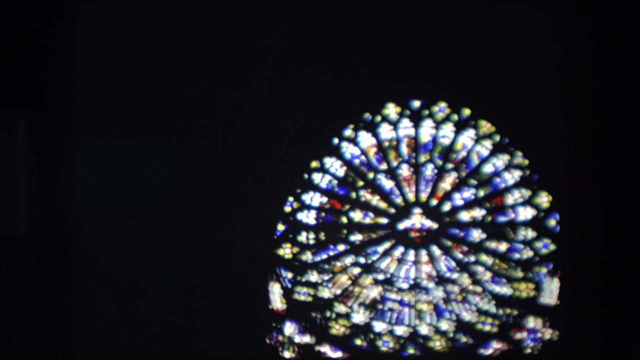 Bright circular stained-glass window glowing in a dark interior.