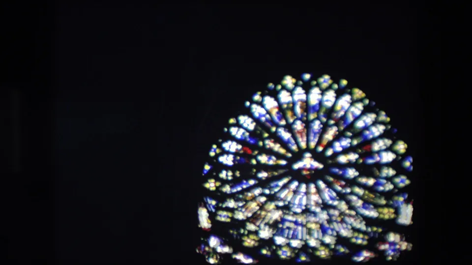 1967 London 8mm frame showing a bright circular stained-glass window with a possible religious center motif against a mostly black interior.