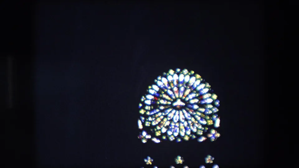 1967 London 8mm frame with a distant glowing stained-glass window and small lower light points in an otherwise dark interior.