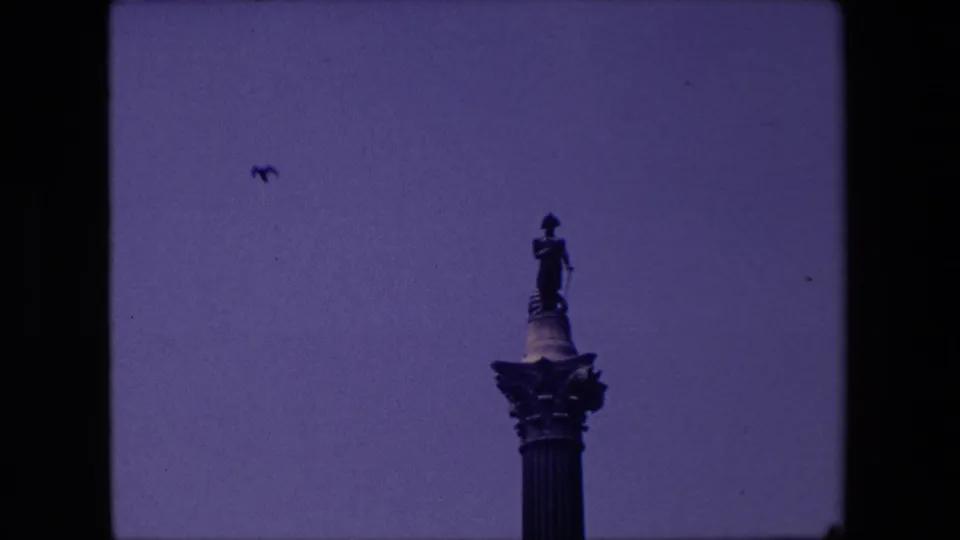 The home-movie camera frames the statue more tightly against the sky, with small birds visible around the monument.