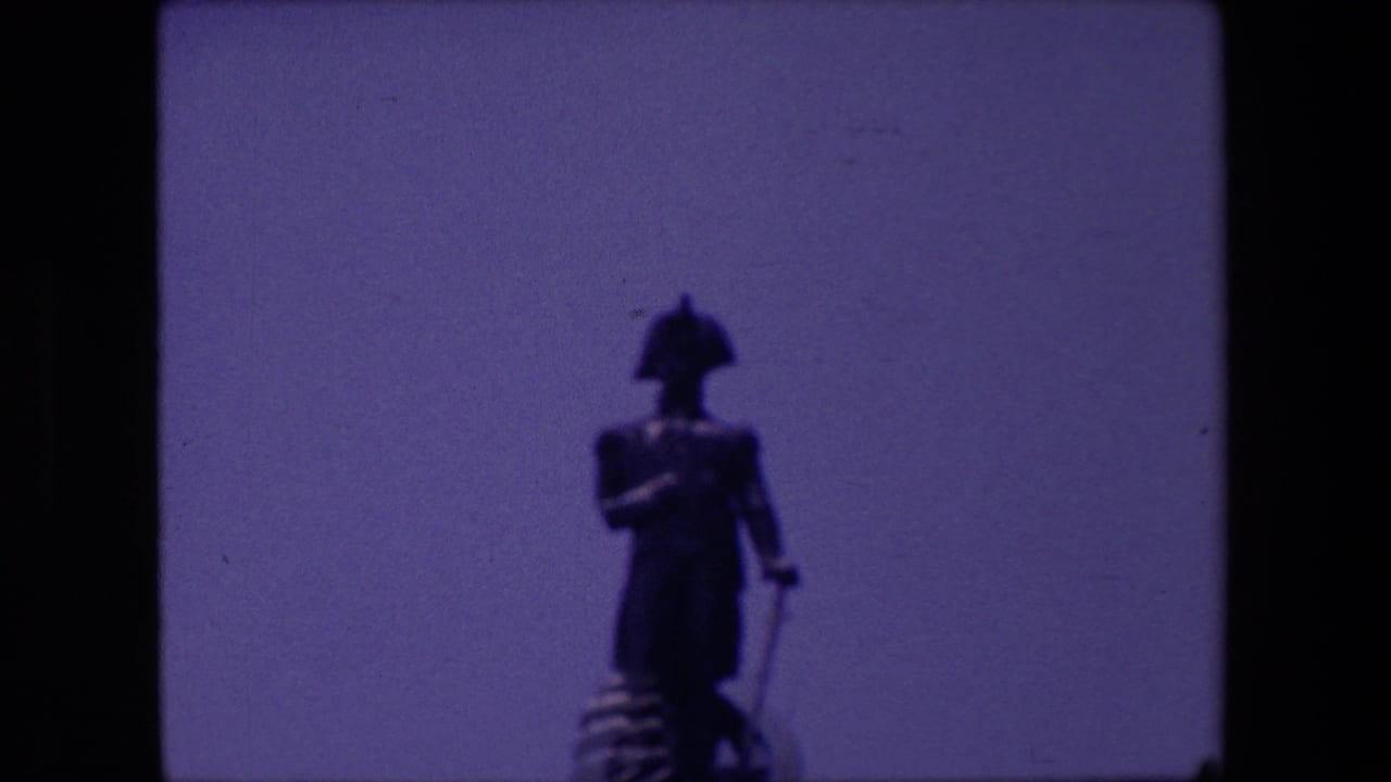 Closer soft-focus view of the same standing statue against sky.