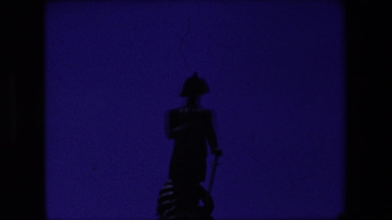 A silhouetted soldier statue appears in the opening frame of 1967 London home-movie footage, with heavy shadow, purple color shift, and visible 8mm frame borders.