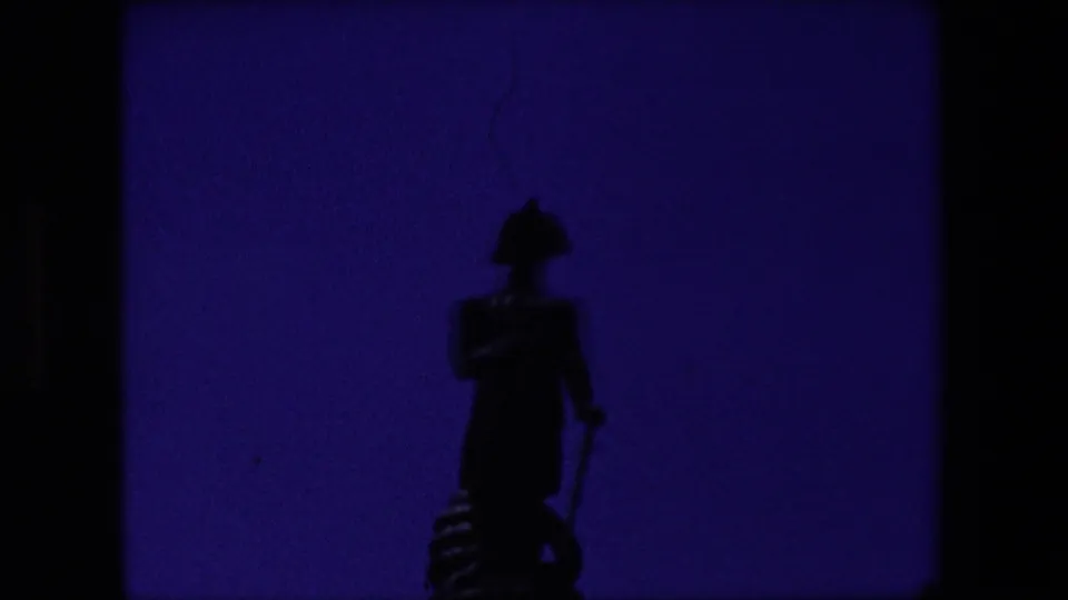 A silhouetted soldier statue appears in the opening frame of 1967 London home-movie footage, with heavy shadow, purple color shift, and visible 8mm frame borders.