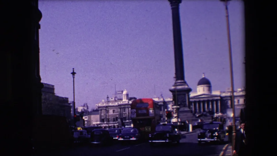 A 1967 London street view shows cars and a red double-decker bus moving past stone civic buildings, tall columns, and a domed facade in the distance.