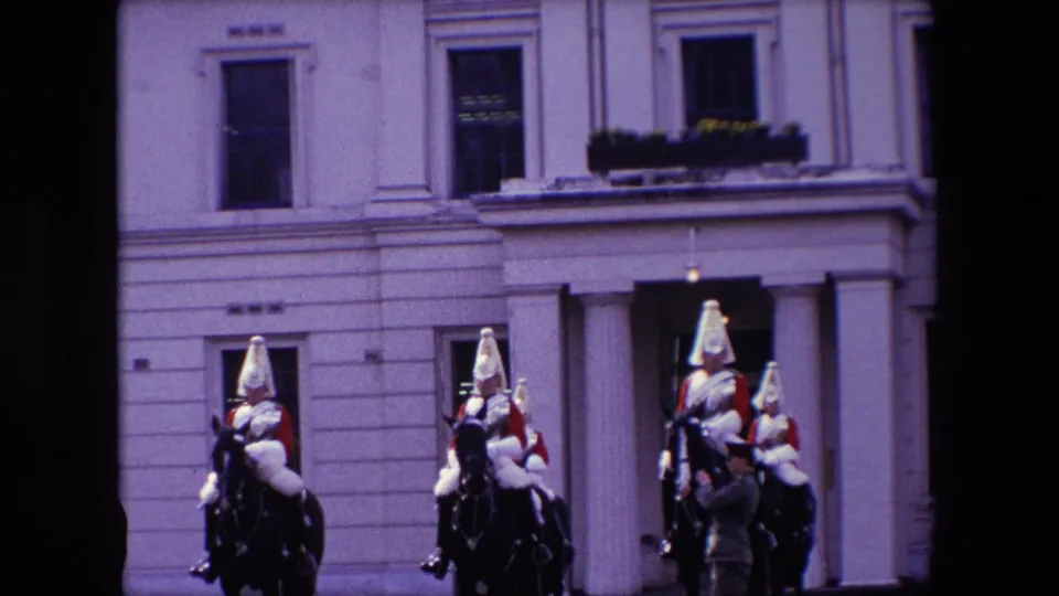 Mounted cavalrymen in dress uniforms appear near a columned entrance in the supplied London ceremonial inspection footage.
