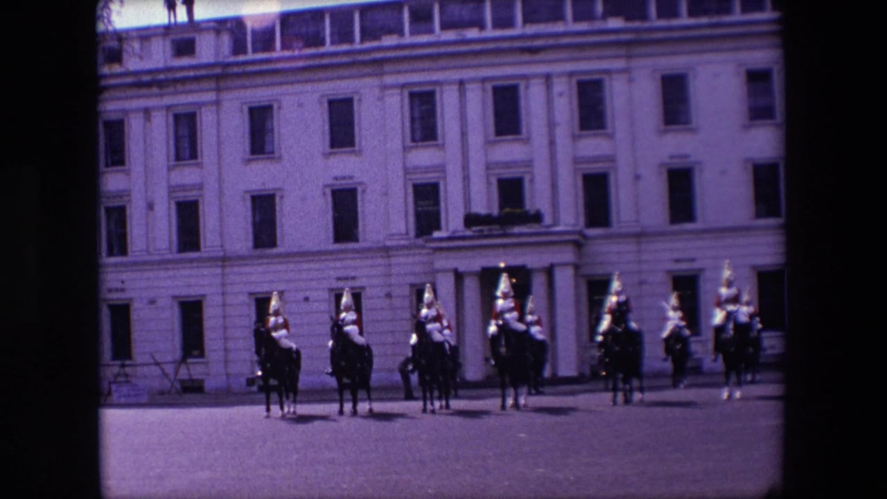 Cavalry riders remain in formation in front of a multi-windowed building.