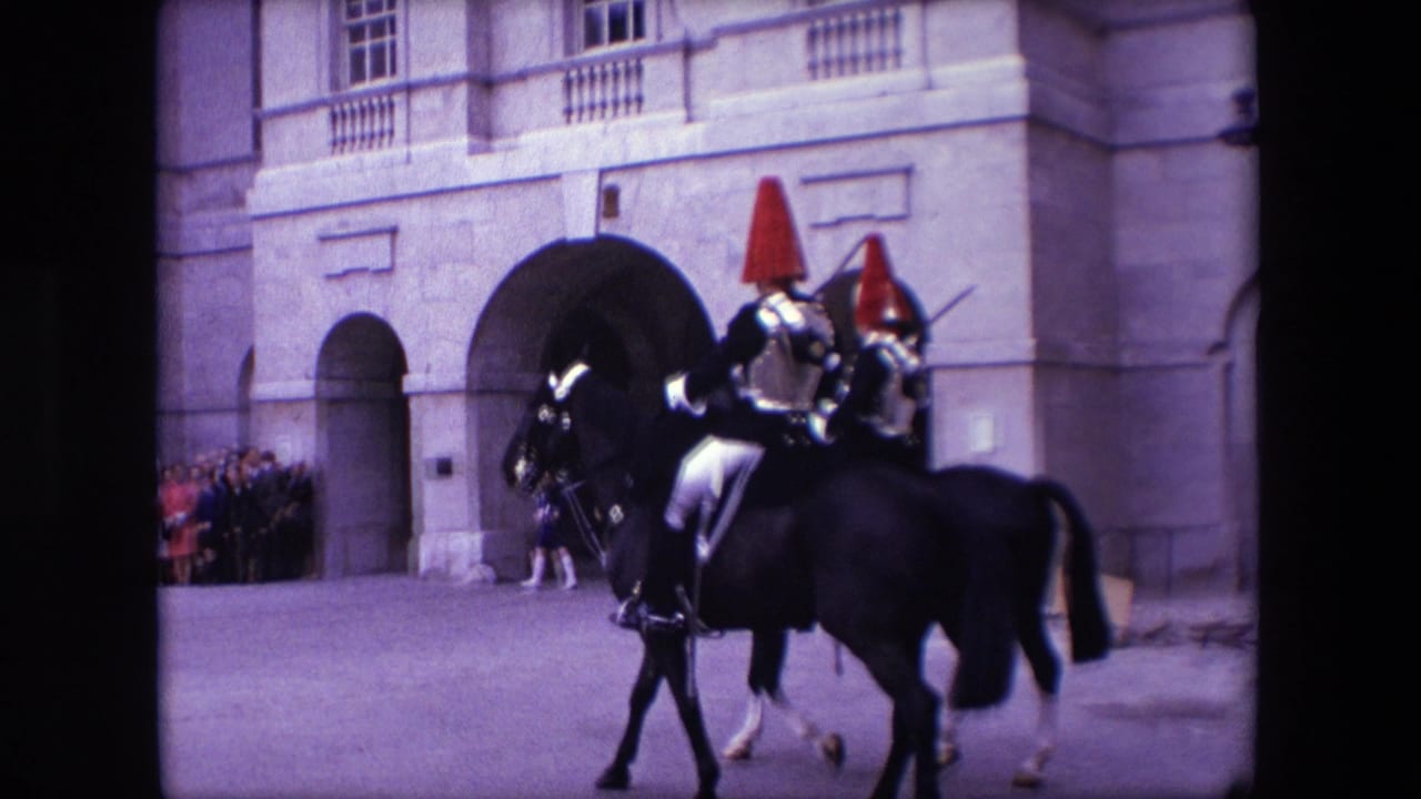 Two mounted ceremonial riders pass in front of a stone arched building entrance.