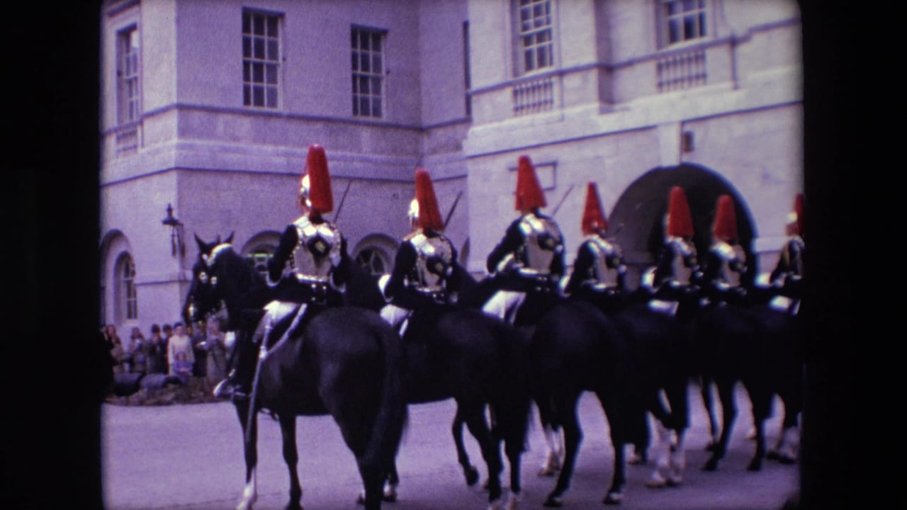 A line of mounted riders in ceremonial armor moves across a courtyard before an arched entrance.