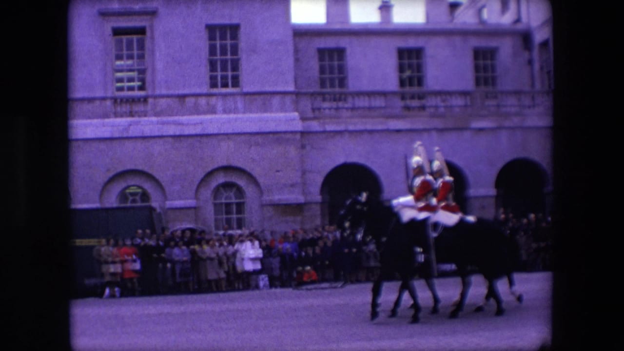 Mounted ceremonial guards ride past a crowd in front of a large stone building.