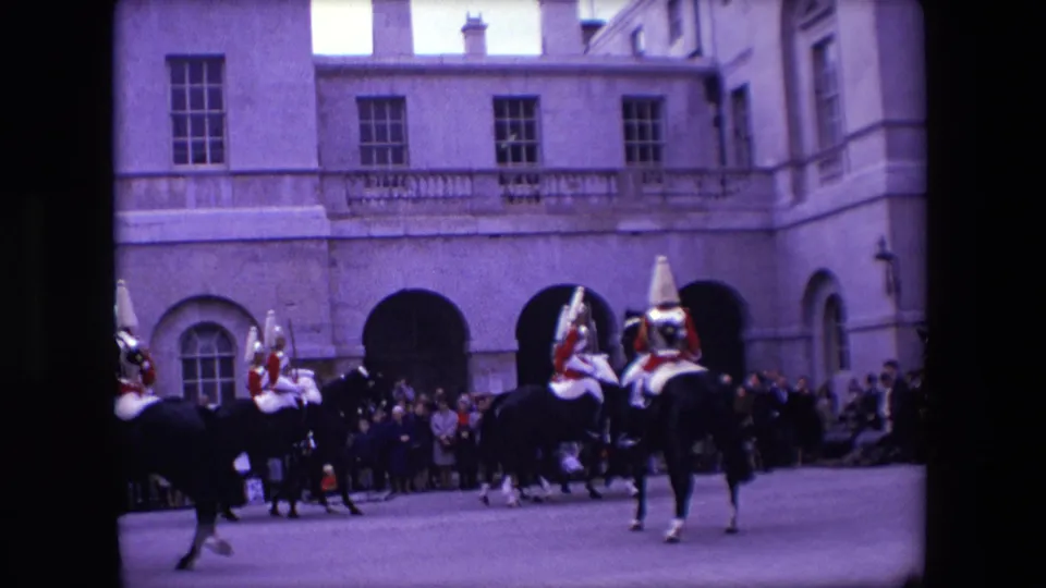 1967 London home-movie still showing the cavalry formation partly exiting frame while onlookers stand near arches and tall windows.