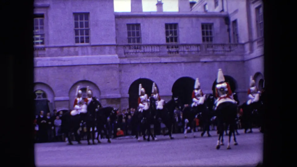 1967 London frame showing mounted uniformed personnel spread across the scene, with a crowd watching from the edge of a formal courtyard or street.