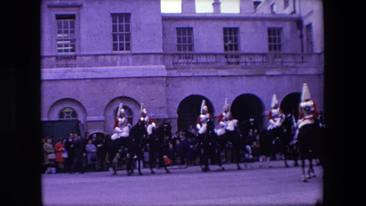 Mounted ceremonial guards ride past spectators in front of a palace facade.
