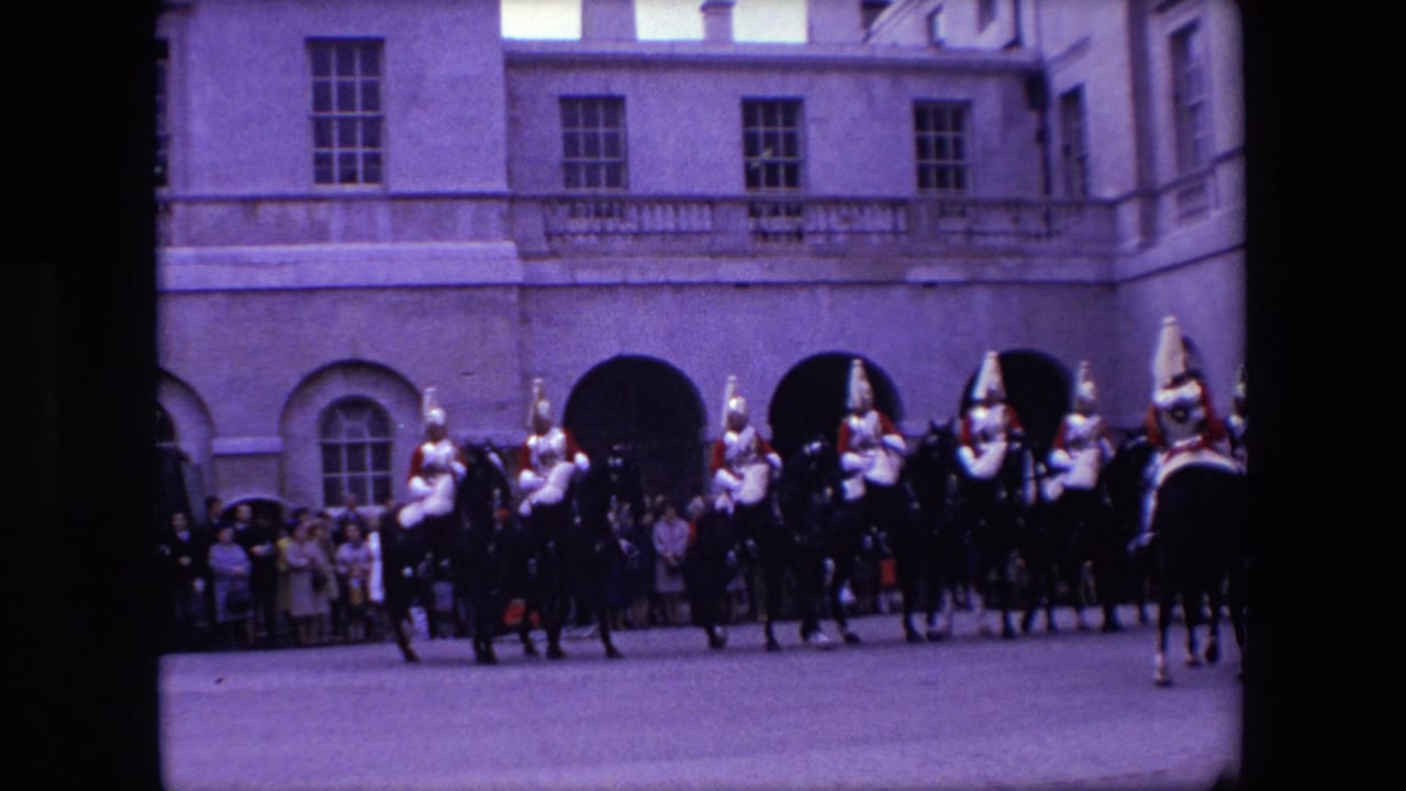A line of mounted guards moves across a courtyard with spectators behind them.