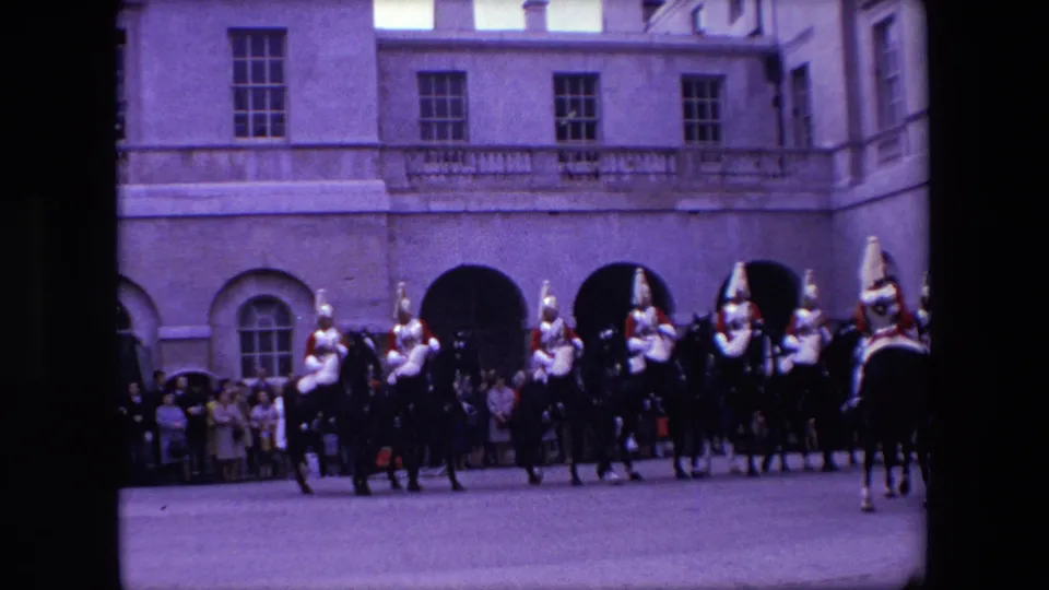 Mounted ceremonial guards cross the palace court while a crowd watches from behind in this 1967 London 8mm frame.