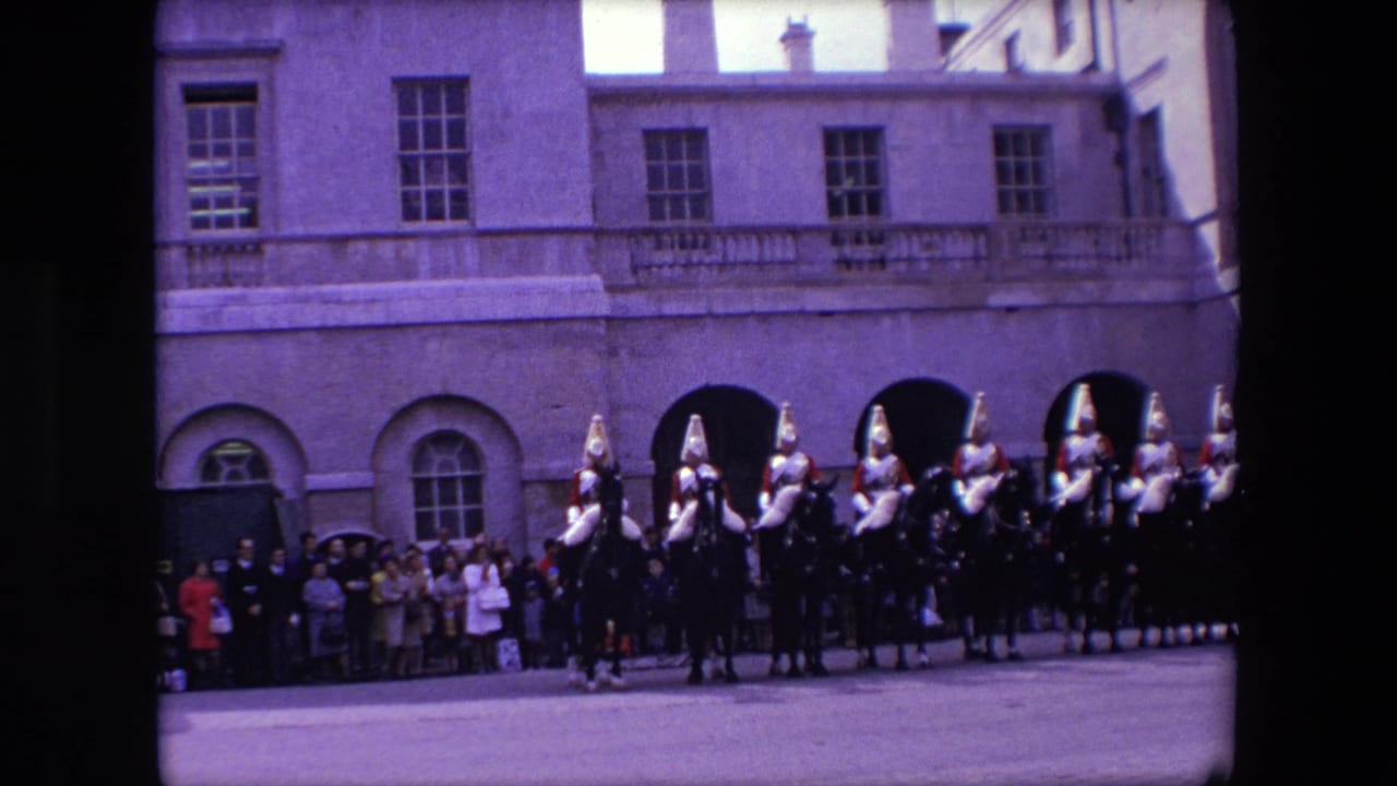 1967 London frame with a line of mounted ceremonial guards near arched openings while a small crowd watches from the building edge.