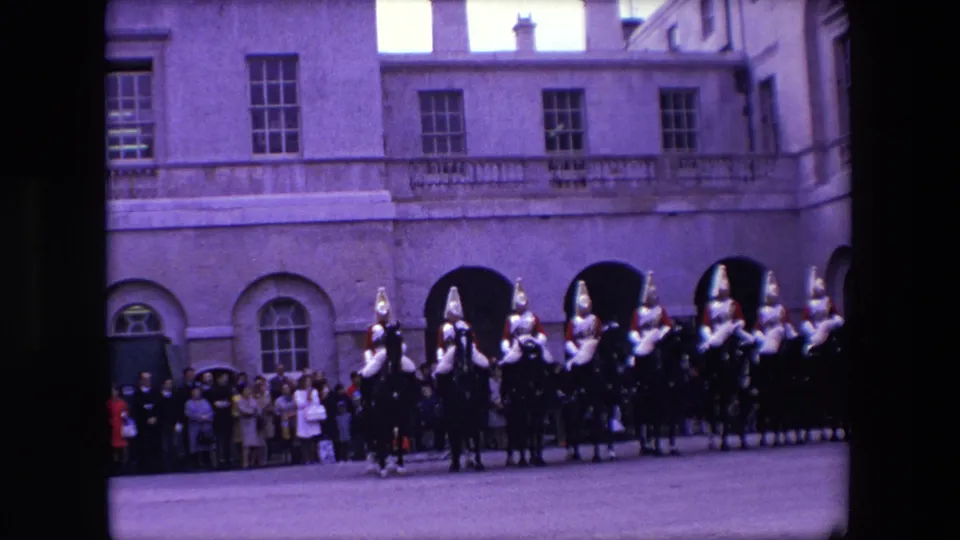 Final 1967 London frame showing mounted guards across the lower scene, with onlookers and formal architecture behind them.
