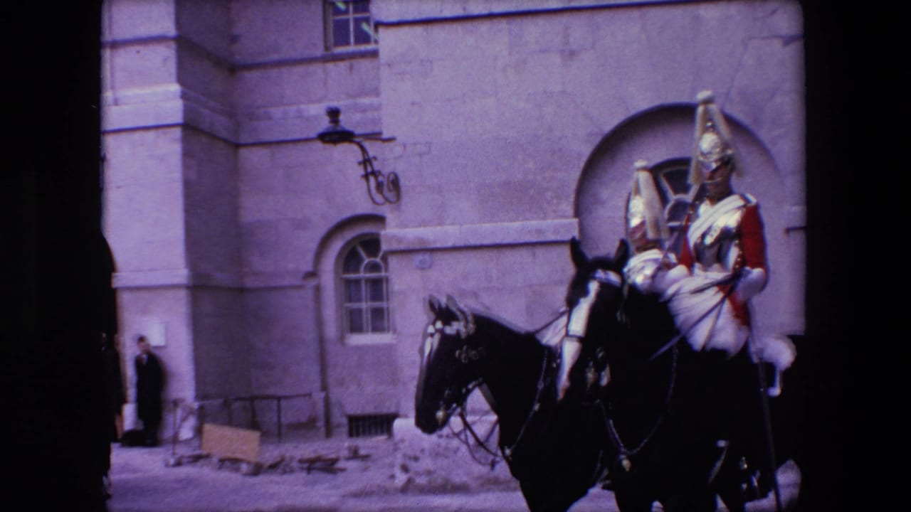 Mounted ceremonial guards riding black horses beside a stone building.