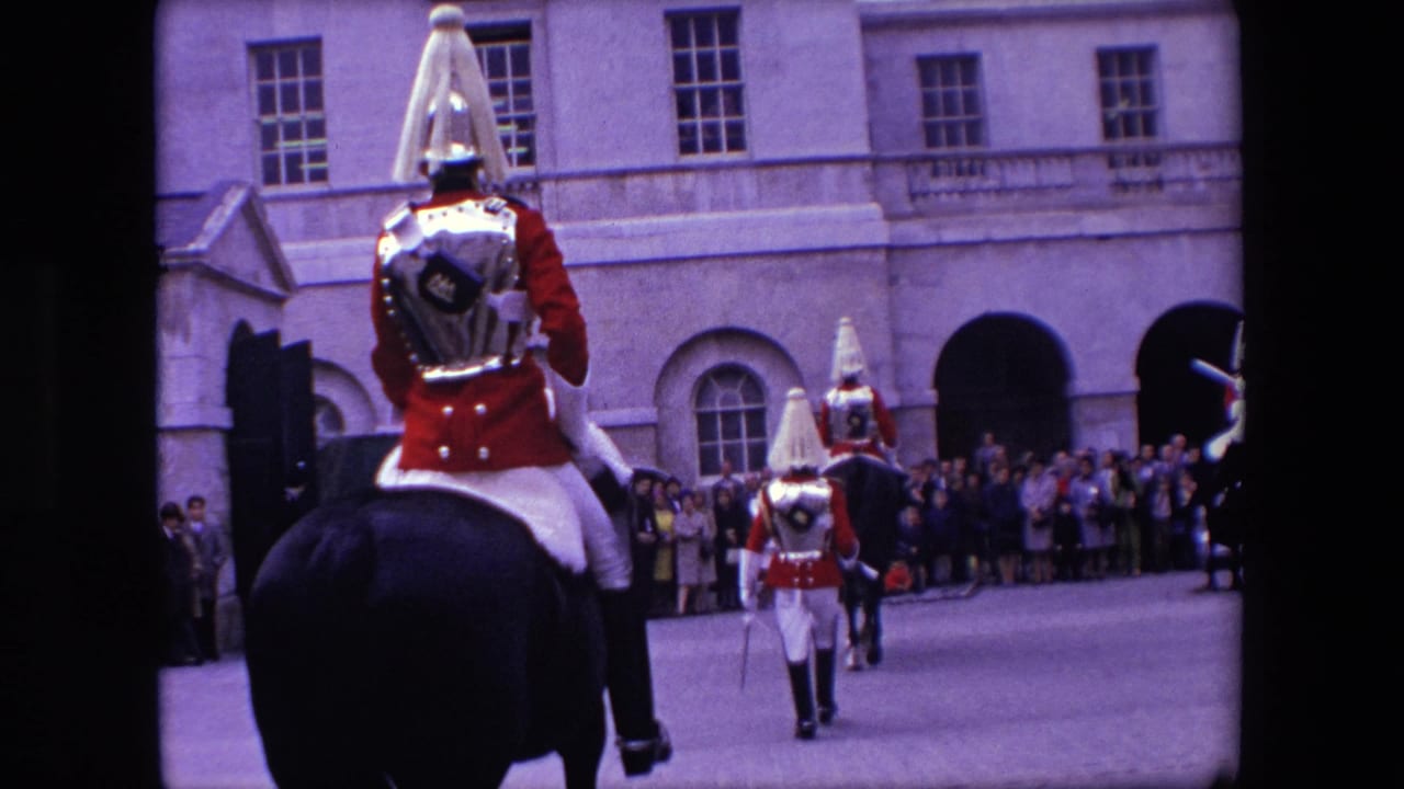 Mounted guards ride through a paved courtyard or street while spectators watch.