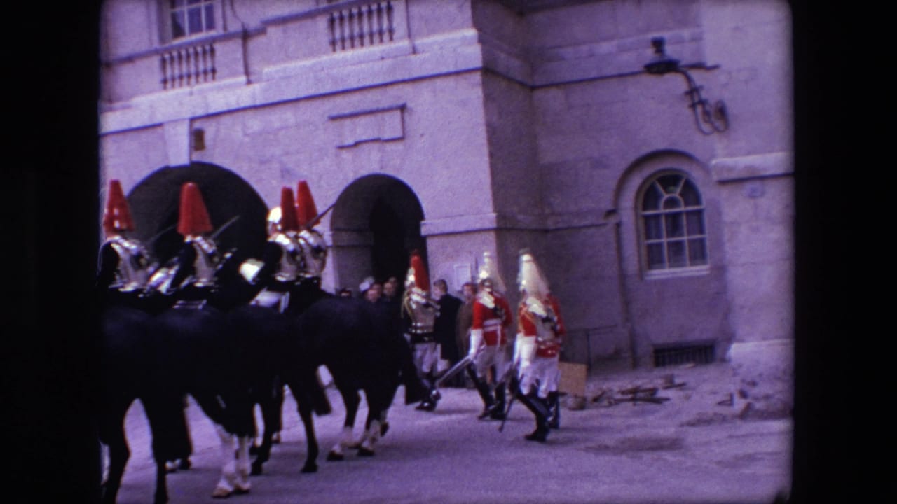Mounted guards and foot guards move across a courtyard beside a stone building.