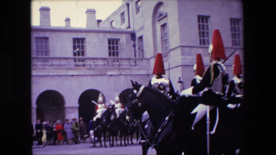 Mounted ceremonial guards and distant spectators appear in a formal London courtyard with arched stone architecture in 1967 home-movie footage.