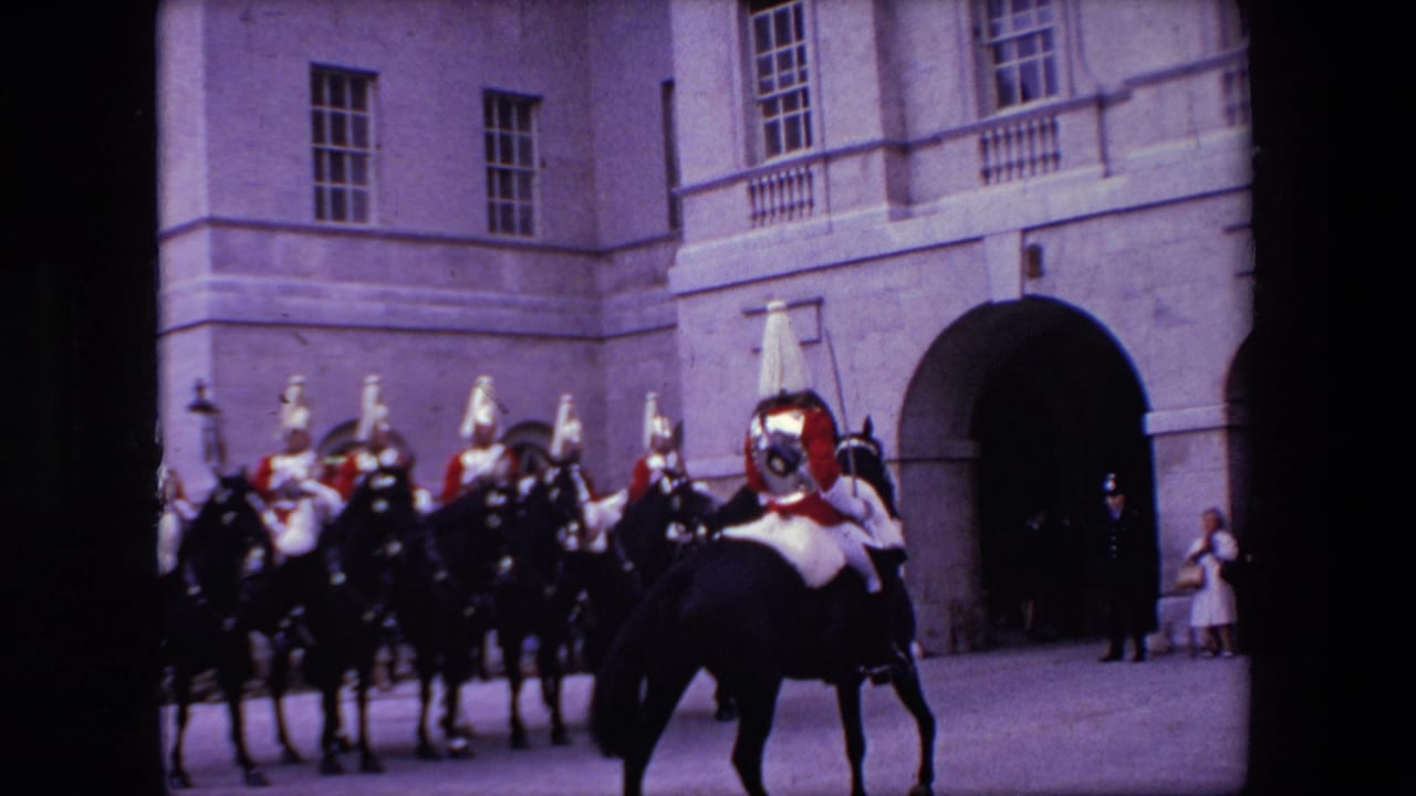 In London, England according to the clip metadata, a lead mounted officer rides ahead of uniformed men on black horses outside a formal stone building.