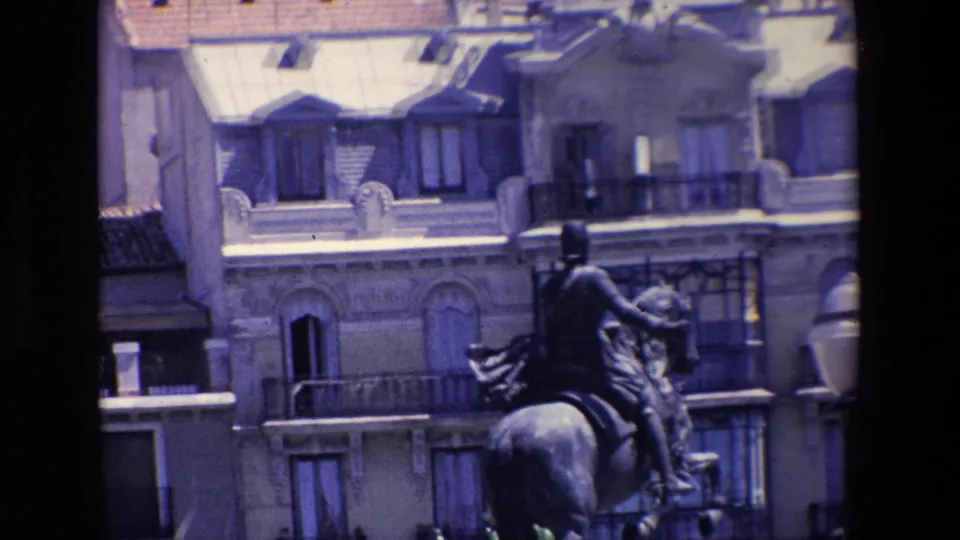 1967 Madrid frame showing a mounted public statue, a globe-topped streetlamp, balconies, dormer windows, and pale stone architecture.