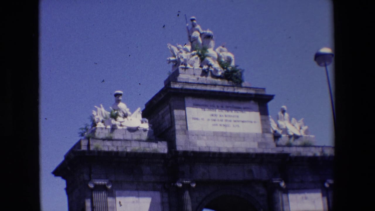Upper portion of a tall stone monument with sculptural figures against blue sky.